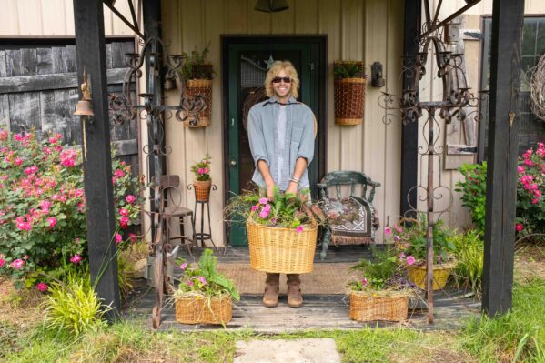 Trace Barnett holding a basket of plants on his front porch