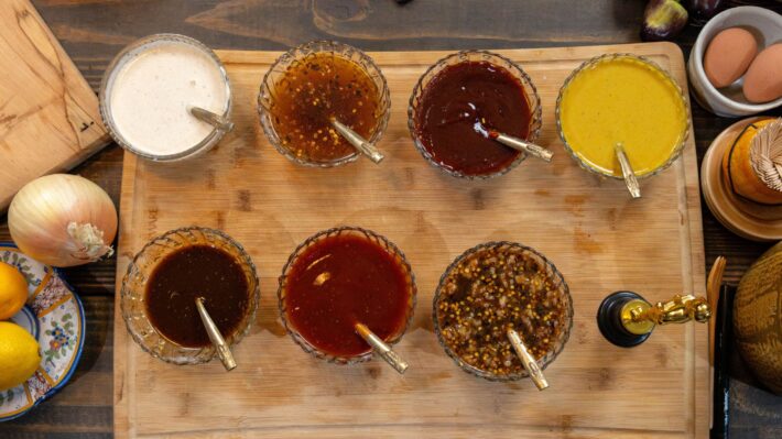 A photo of 7 BBQ sauces lined up together along with an Emmy trophy